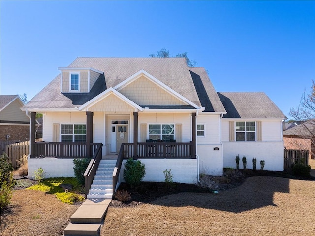 view of front of home with roof with shingles, fence, and covered porch