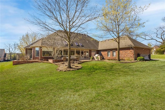 back of property with brick siding, a patio, and a lawn