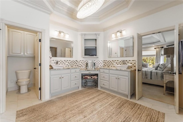ensuite bathroom with ornamental molding, toilet, a tray ceiling, decorative backsplash, and marble finish floor