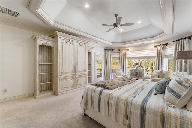 bedroom with a raised ceiling, light colored carpet, ornamental molding, and visible vents