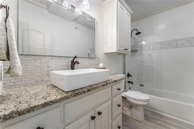 bathroom featuring shower / washtub combination, ornamental molding, toilet, wood finished floors, and backsplash