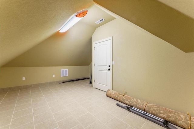 additional living space featuring a textured ceiling, lofted ceiling, and visible vents