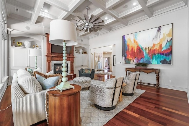 living room featuring a glass covered fireplace, ornamental molding, a ceiling fan, beam ceiling, and wood finished floors