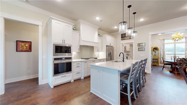 kitchen featuring a center island with sink, dark wood-style floors, tasteful backsplash, and stainless steel appliances