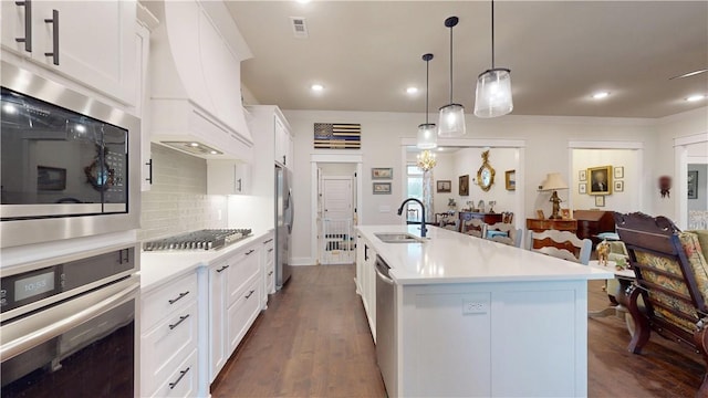 kitchen featuring light countertops, a sink, dark wood finished floors, backsplash, and stainless steel appliances