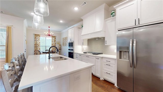 kitchen featuring a kitchen island with sink, backsplash, visible vents, appliances with stainless steel finishes, and a sink