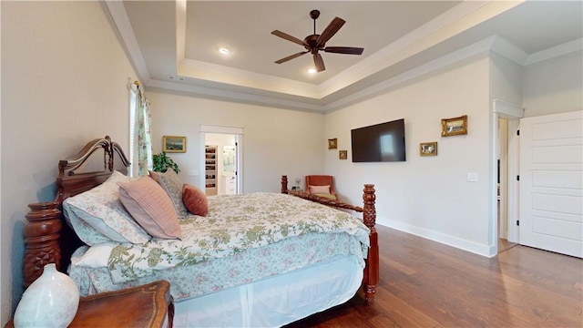 bedroom with crown molding, wood finished floors, baseboards, a raised ceiling, and a ceiling fan