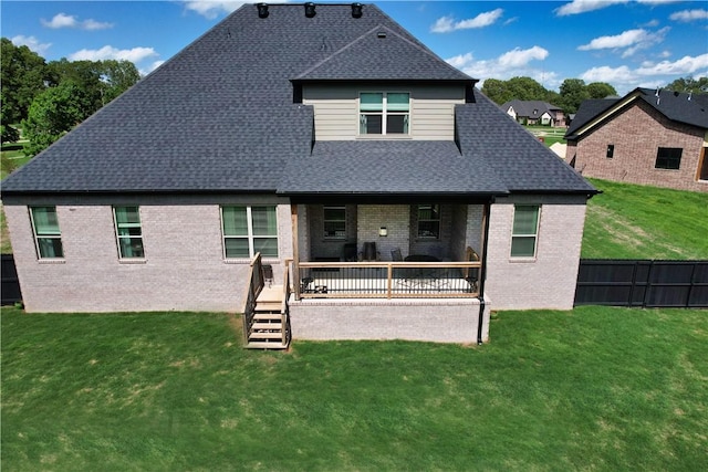 back of house featuring a deck, brick siding, a fenced backyard, a yard, and a shingled roof