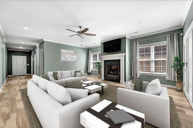 living room with crown molding, baseboards, ceiling fan, and light wood-style floors