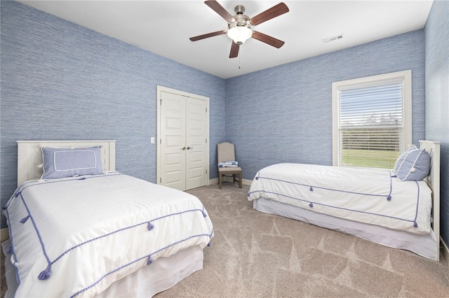 carpeted bedroom with visible vents, a ceiling fan, a closet, and wallpapered walls