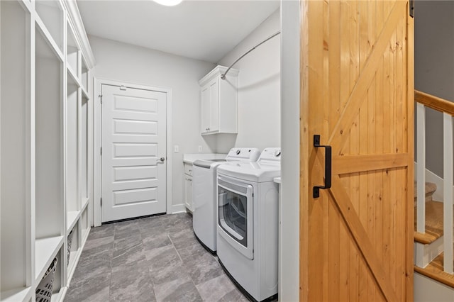 laundry area with cabinet space, independent washer and dryer, a barn door, and baseboards