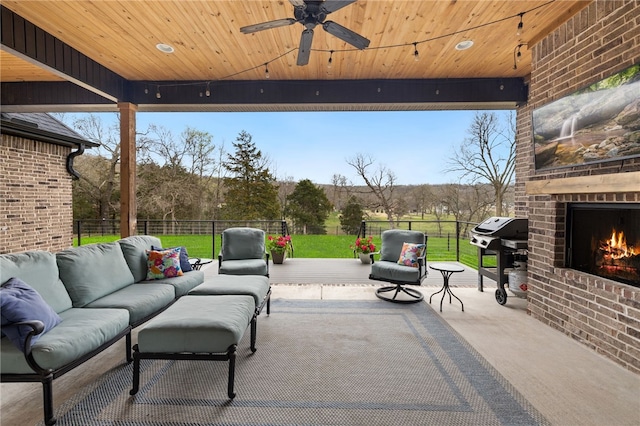 view of patio / terrace featuring area for grilling, ceiling fan, an outdoor living space with a fireplace, and fence
