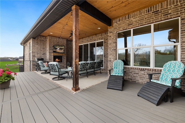 wooden terrace with an outdoor living space with a fireplace and a ceiling fan
