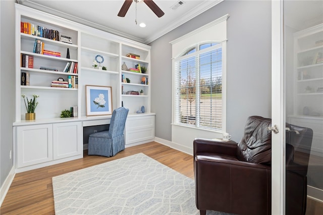home office featuring ceiling fan, light wood-style flooring, ornamental molding, visible vents, and built in desk