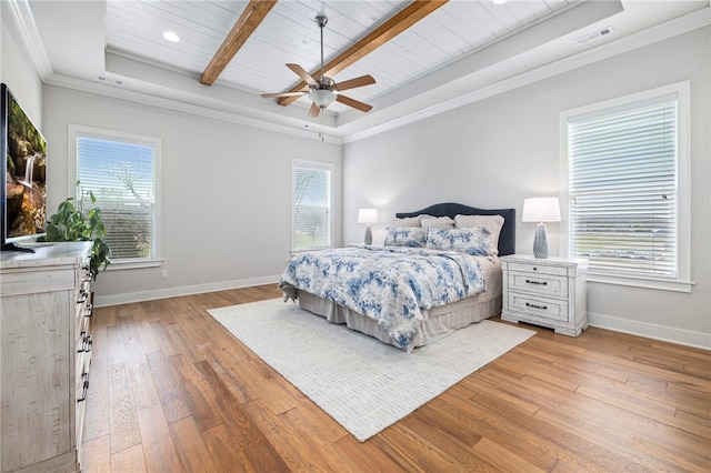 bedroom featuring light wood-style floors, visible vents, a tray ceiling, and multiple windows