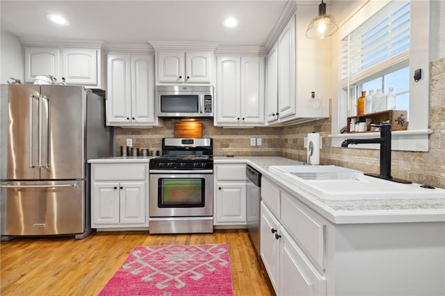 708 NW B St, Bentonville, AR 72712 - kitchen featuring a sink, light countertops, stainless steel appliances, light wood-style flooring, and white cabinets