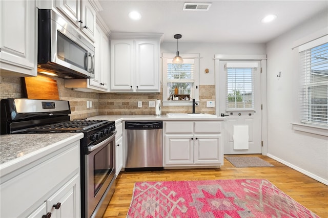 708 NW B St, Bentonville, AR 72712 - kitchen with a sink, visible vents, white cabinetry, light countertops, and appliances with stainless steel finishes