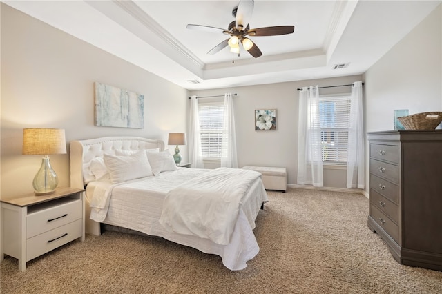 bedroom with a tray ceiling, multiple windows, visible vents, and light carpet