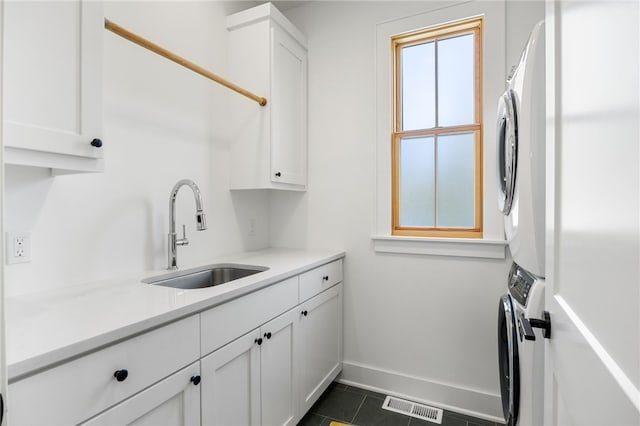 kitchen featuring white cabinets, visible vents, a sink, light countertops, and stacked washing maching and dryer