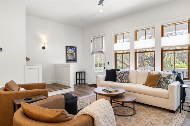 living area featuring light wood-style floors, a healthy amount of sunlight, baseboards, and a ceiling fan