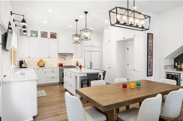 dining space featuring recessed lighting, light wood-style floors, beverage cooler, and an inviting chandelier