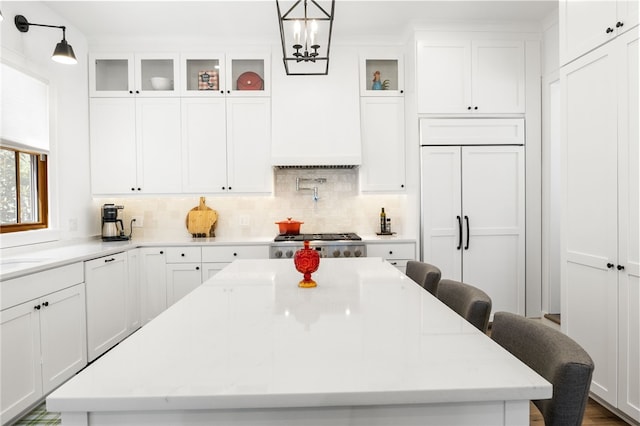 kitchen with a breakfast bar area, paneled appliances, white cabinets, and a kitchen island