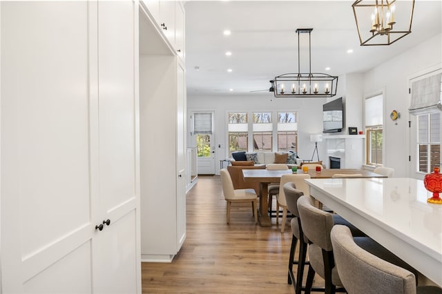 dining space with a chandelier, light wood-style floors, a glass covered fireplace, and recessed lighting