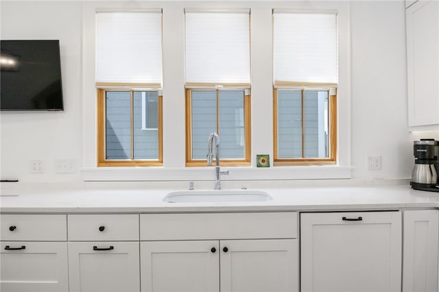 kitchen with white cabinets, light countertops, and a sink