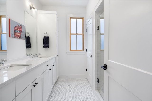 bathroom featuring a sink, baseboards, double vanity, and a shower stall