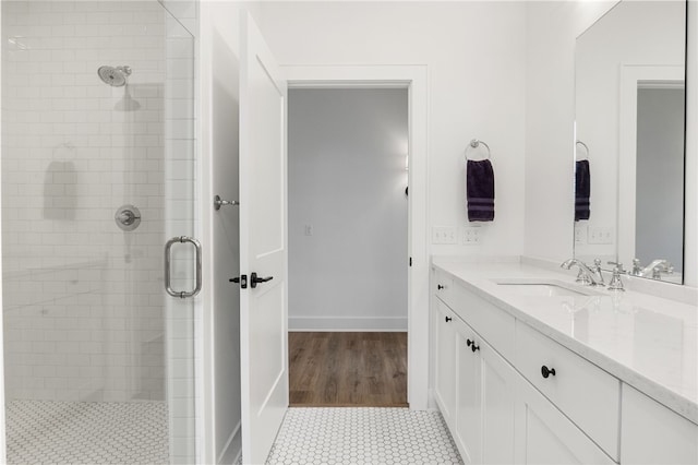 full bath featuring vanity, baseboards, and a stall shower