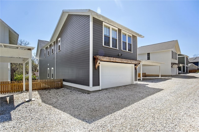 view of side of home featuring driveway, fence, and a garage