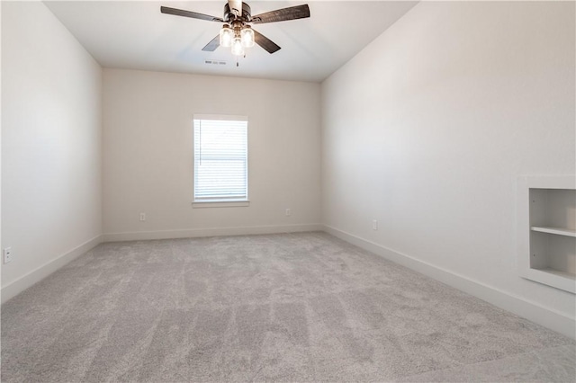 unfurnished room featuring ceiling fan, light colored carpet, baseboards, and built in shelves