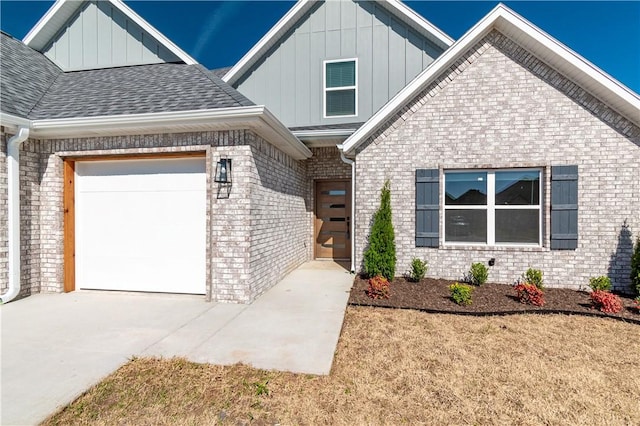 view of front of house with board and batten siding, brick siding, an attached garage, and a shingled roof