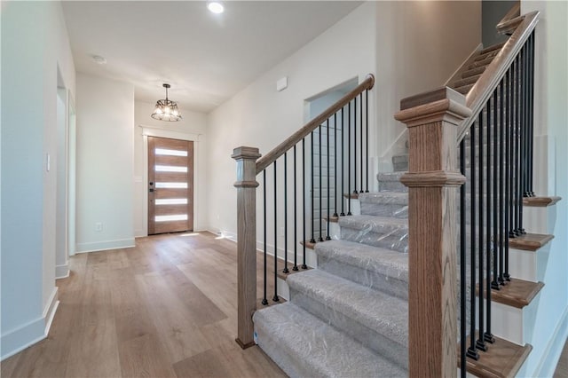 foyer entrance with wood finished floors, stairs, and baseboards