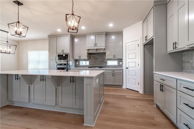 kitchen featuring a chandelier, gray cabinets, stainless steel appliances, tasteful backsplash, and recessed lighting