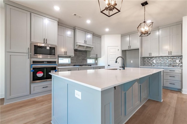 kitchen featuring stainless steel appliances, a chandelier, a sink, light wood-style floors, and recessed lighting