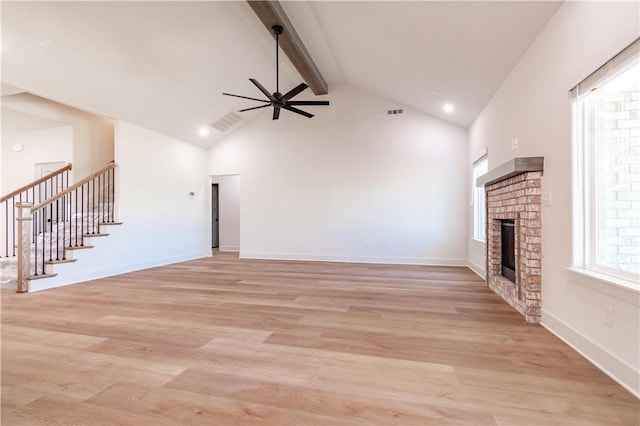unfurnished living room featuring a brick fireplace, a ceiling fan, beam ceiling, stairs, and high vaulted ceiling