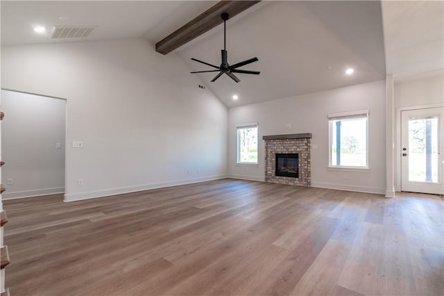 unfurnished living room featuring a ceiling fan, beam ceiling, high vaulted ceiling, a brick fireplace, and wood finished floors