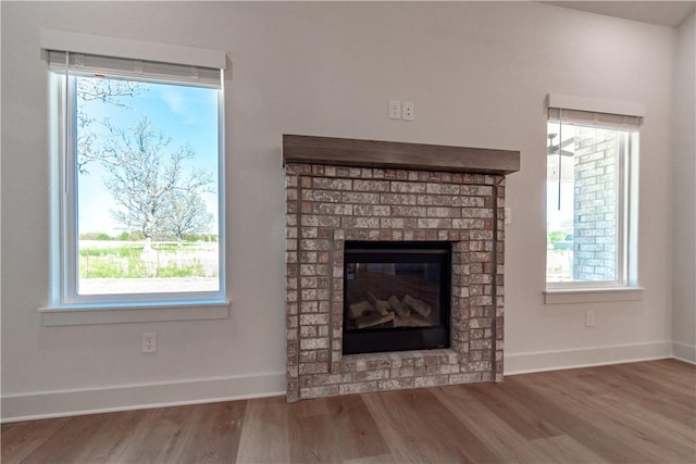 detailed view of wood finished floors, a fireplace, and baseboards
