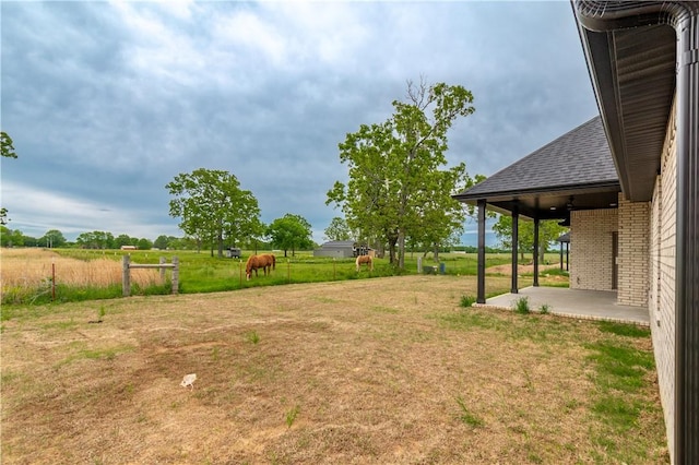 view of green lawn featuring a patio area and a view of countryside