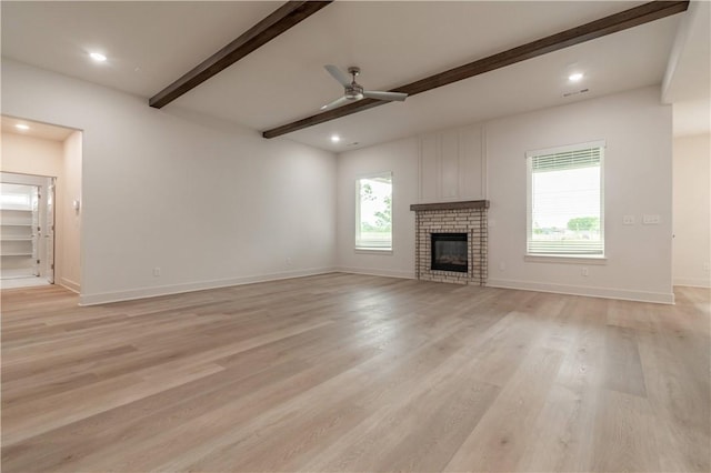 unfurnished living room featuring beam ceiling, light wood-style flooring, ceiling fan, a fireplace, and baseboards