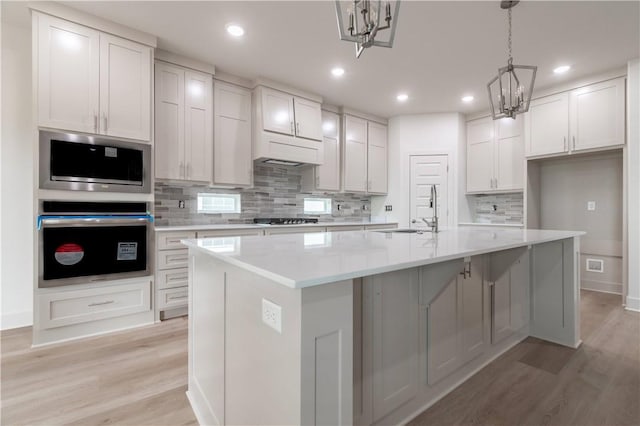 kitchen featuring a sink, light wood finished floors, tasteful backsplash, light countertops, and recessed lighting