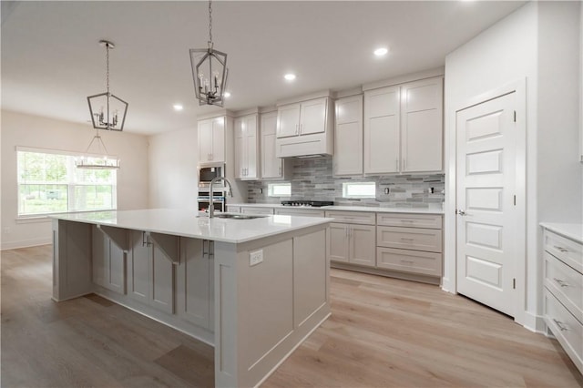 kitchen featuring a sink, a chandelier, light wood-type flooring, decorative backsplash, and recessed lighting