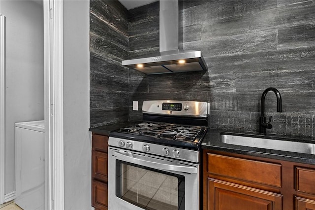 kitchen featuring wall chimney exhaust hood, tasteful backsplash, a sink, stainless steel gas range oven, and brown cabinets