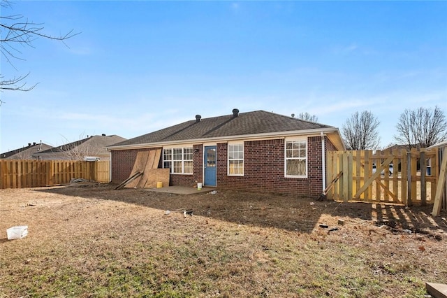 rear view of property with a gate, fence private yard, and brick siding