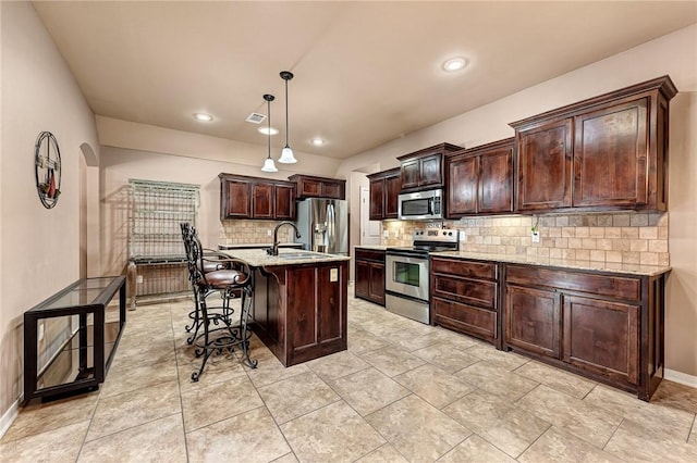 3207 SW Stonepoint Ave, Bentonville, AR 72712 - kitchen featuring appliances with stainless steel finishes, dark brown cabinetry, a kitchen bar, and light stone countertops