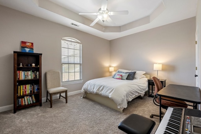bedroom featuring a raised ceiling, carpet, baseboards, and ceiling fan