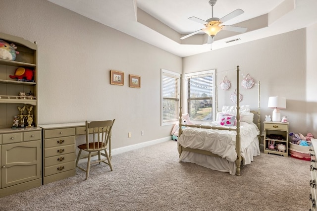 carpeted bedroom with a raised ceiling, baseboards, and ceiling fan