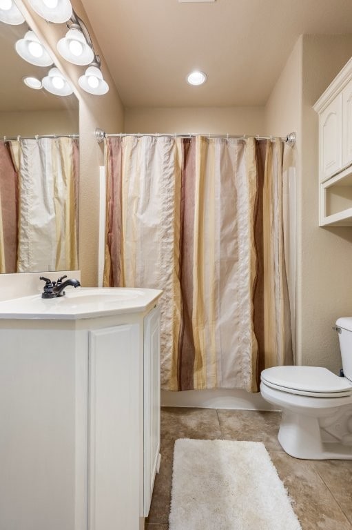 bathroom with toilet, vanity, and tile patterned flooring