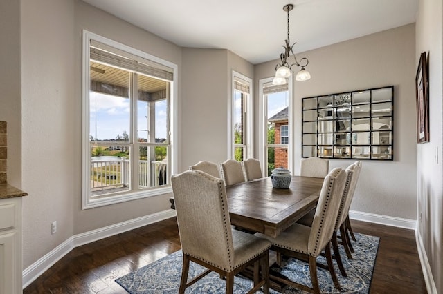 dining space with baseboards, healthy amount of natural light, dark wood-style flooring, and a chandelier